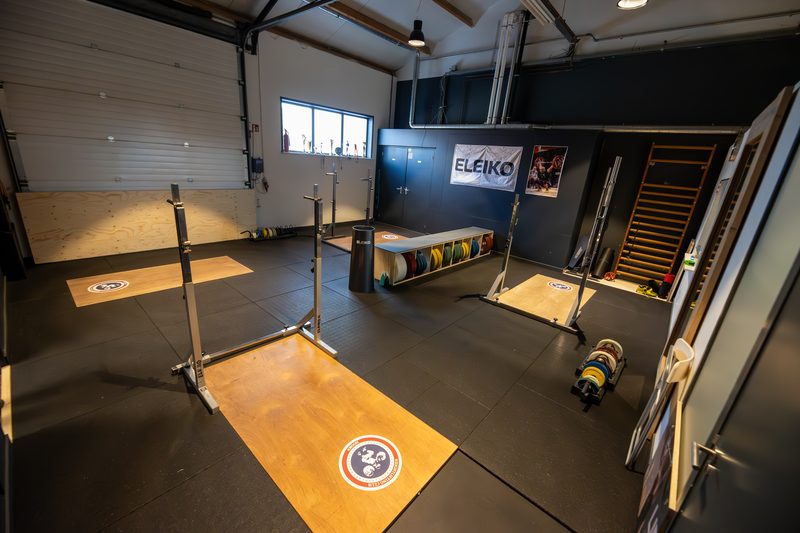 De zaal van Weightlifting Club Hoorn met squatrekken, heftplatforms en een wandrek.